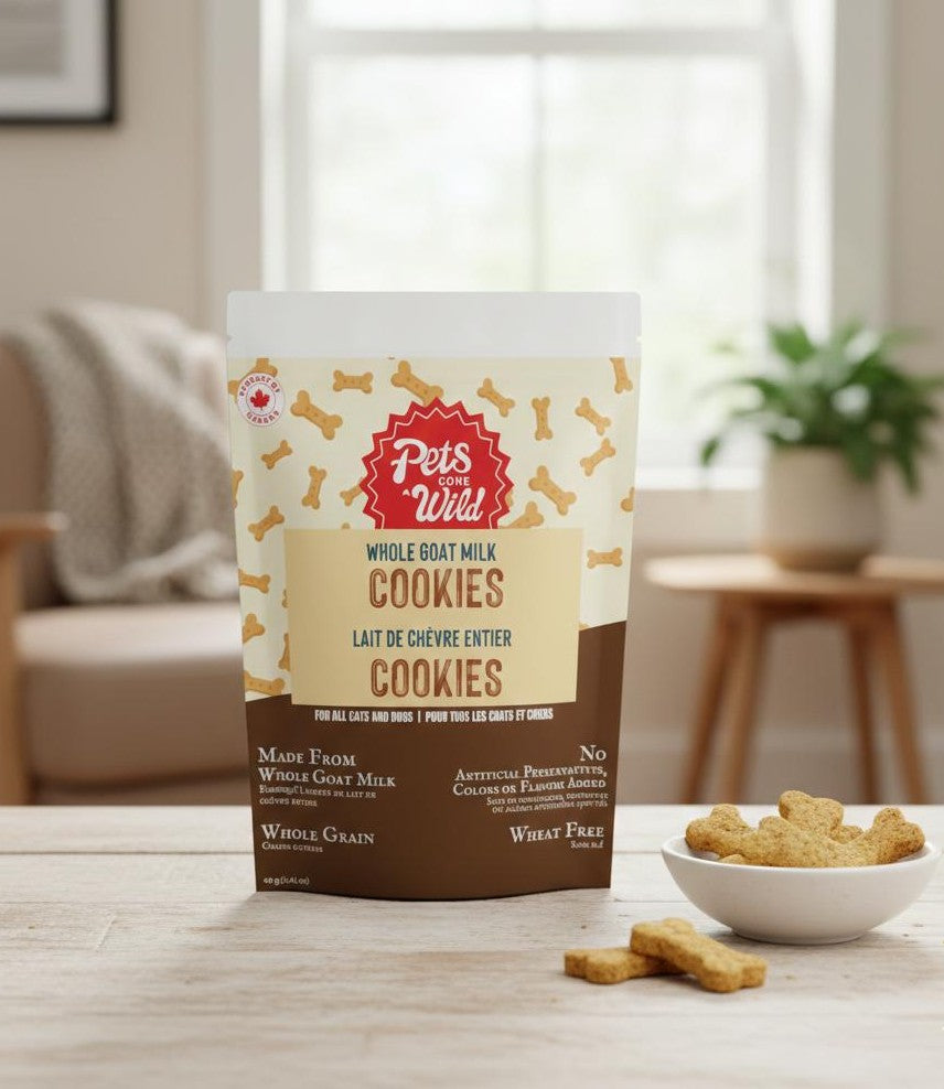 Package of Pets Gone Wild goat milk peanut butter cookies for medium and large dogs and cats on a table with baked cookies and a bowl, medium and large size, slow-baked in Canada, xylitol-free, 6 real ingredients