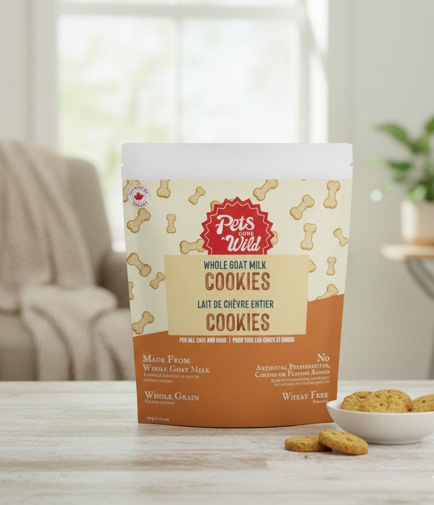 Package of Pets Gone Wild whole goat milk peanut butter cookies for puppies, small dogs, and cats on a table with baked cookies and a bowl in the background, slow-baked in Canada, xylitol-free, 6 real ingredients